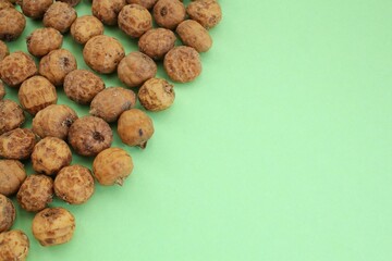 Top view of chufa, tigernut, earth almond on green background with copy space for text. Healthy organic vegan food concept. Tiger nut for flour, oil, milk, traditional drink horchata from Valencia