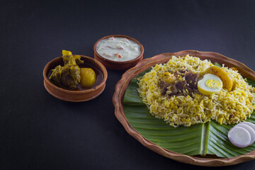 Kolkata style mutton biryani with potato and egg served on clay plate and banana leaf with mutton...