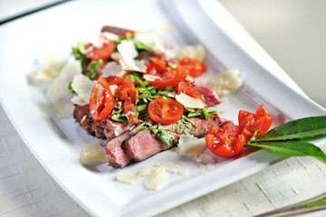 Ribeye steak on the bone sliced in a rectangular dish
