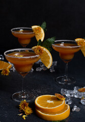 Glasses of orange cocktail decorated with orange and sugar on the edge of glass on black background