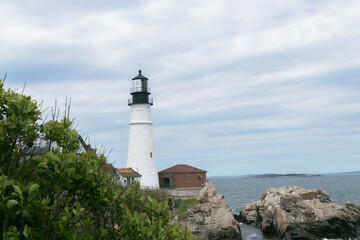 Fototapeta na wymiar Lighthouse on coast during day against cloudy sky