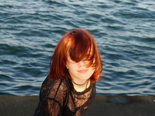 portrait of a smiling red-haired teenage girl against the backdrop of the sea