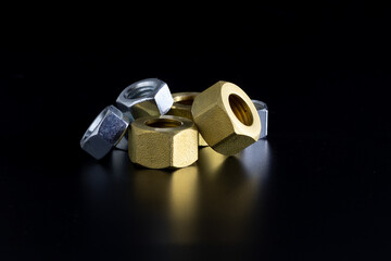 Group of Silver and Gold Hardware Nuts on Reflective Black Surface