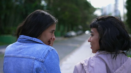 Fototapeta premium Back two young women walking outside together. Two female friends chatting