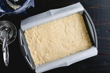 Dessert Bar Crust Pressed into a Metal Baking Pan: Unbaked pastry crust in a parchment paper lined brownie pan