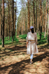 a woman walks along the road through a young pine forest