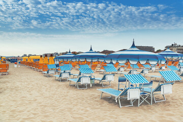 Beach in Rimini, Italy. Umbrellas on sandy beach in resort city Rimini on morning. Summer vacation to sea rest in Rimini