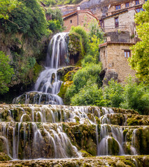 Cascada que cae entre las casas de un pueblo en la sierra de Burgos.