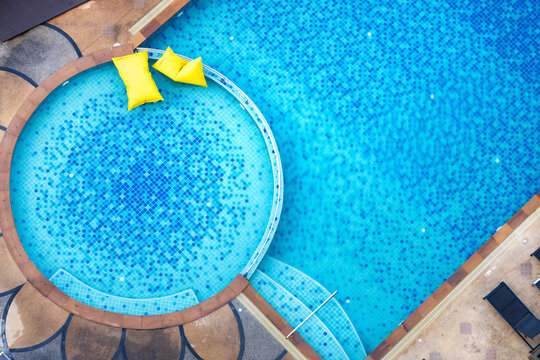 Aerial view of yellow pool floating tube in blue swimming pool. High view from above.