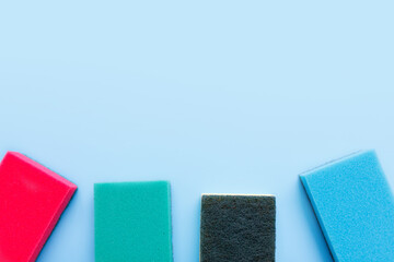 Multicolored sponges for cleaning on a blue background. Space for text.