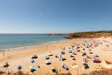 Fototapeta na wymiar beach of the coast of southern Spain in summer. image of a sandy beach full of tourists with towels and umbrellas to protect themselves from the sun. vacation and relaxation concept in summer