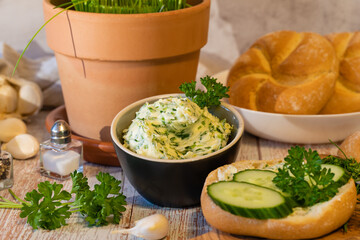 Spicy herb butter, fresh rolls and chopped herb ingredients on cutting board