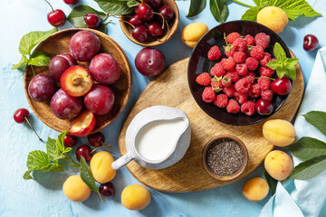 Ingredients for a healthy smoothie. Milk and berries (raspberry, cherry, plum, apricot) on a stone tabletop. Healthy eating, raw food diet and vegan food concept. View from above.