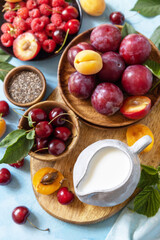 Ingredients for a healthy smoothie. Milk and berries (raspberry, cherry, plum, apricot) on a stone tabletop. Healthy eating, raw food diet and vegan food concept. View from above.