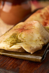 Ranchero tamales with red and green sauce placed on their banana leaf and on wood to cut, mexican food from veracruz