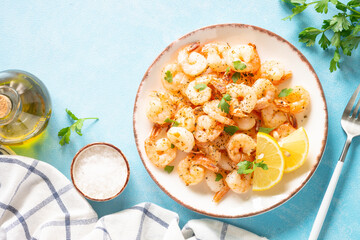 Fried shrimps with herbs and olive oil at blue table. Top view with space for your text.