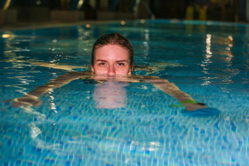 a girl swims in the pool in the evening