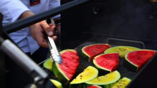 Man turning grilled watermelon upside down, red and yellow watermelon cooking. High quality FullHD footage