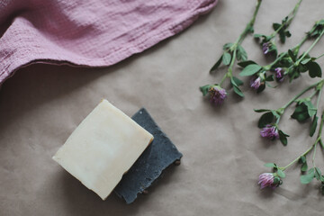 Natural organic soap with flowers and pink towel on craft paper background top view with copyspace