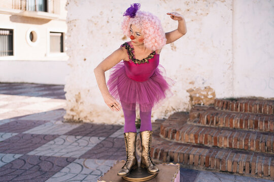 Funny female clown pretending to be ballerina during street performance