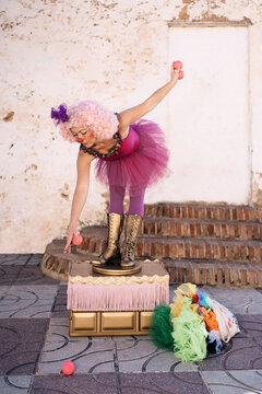 Female circus artist practicing juggling on street
