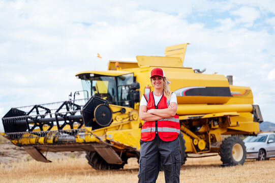 Content woman standing near combine harvester