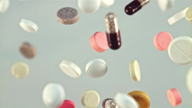 A bunch of different pills fly up and rotate in flight. On a white background. Filmed is slow motion 1000 fps.