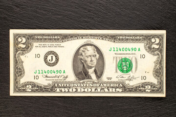 One 1976 US two dollar bill on a slate stone, close-up, top view.
