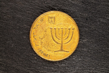 One Israeli metal coin on a slate stone, close-up, top view.