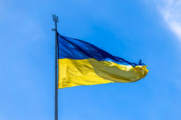 The national flag of Ukraine flies on wind in the blue sky