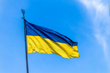 The national flag of Ukraine flies on wind in the blue sky