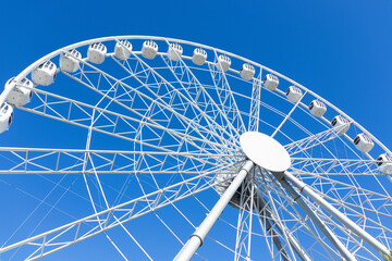 White big ferris wheel against blue sky, bottom-up view