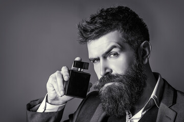 Masculine perfumery, bearded man in a suit. Male holding up bottle of perfume. Man perfume,...
