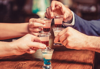 Group friends tequila shot glasses in bar. Male hands glasses of shot or liqueur. Friends drink shot or liqueur. Five glasses of alcohol.Tequila shots, vodka, whisky, rum