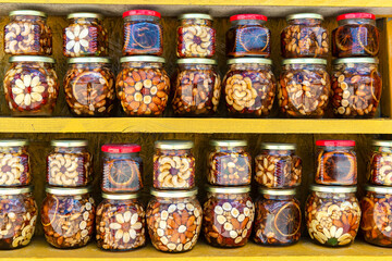 Fototapeta na wymiar Jars of sweets with fresh honey and nuts in selective focus are sold at an outdoor farmers market. Agricultural honey fair. Sale of healthy and wholesome food.