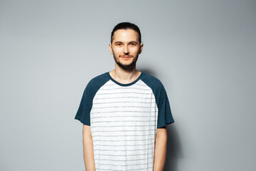 Studio portrait of serious guy on grey background, wearing white shirt with blue.