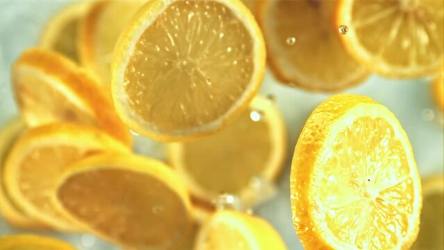 Slices of lemon with drops of water slowly rotate in flight. On a white background. Top view. Filmed is slow motion 1000 fps.