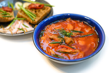 dish of ukrainian borsch with meat, bread and greens ready to eat on white background