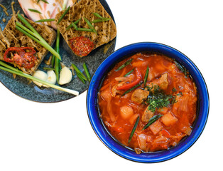 dish of ukrainian borsch with meat, bread, garlic and greens ready to eat on white background