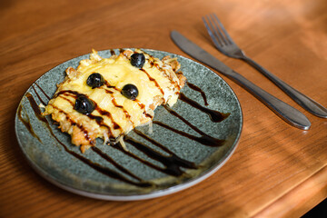 chop grated with cheese and served with olives on plate with cutlery on wooden backround