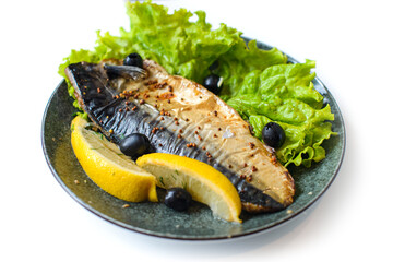 mackerel baked in french mustard sauce with slice of lemon, lettuce and olives on plate on white background