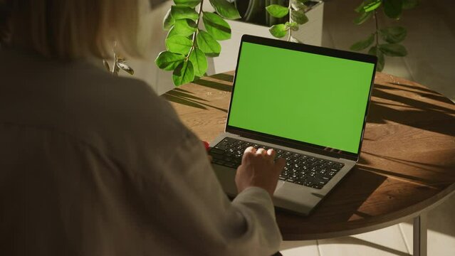 Handheld shot of a caucasian woman hand scrolling and pressing enter on a laptop with green screen