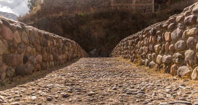 stone path close to stone construction with distant bushes in checacupe, cusco, peru