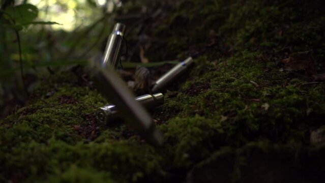 Bullet casings fall on the moss. Shooting in the forest.