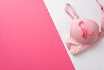 Breast cancer awareness concept. Top view photo of pink ribbon attached to pink bra on bicolor pink and white background with copyspace - obrazy, fototapety, plakaty