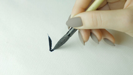 Woman's hands writing Chinese hieroglyph. Female hand holding a writing brush calligraphy Chinese...