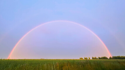 Fototapeta na wymiar full rainbow in the field by the road. double rainbow
