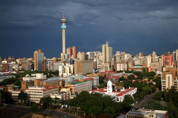 Fototapeta premium overview over downtown of Johannesburg with TV-tower and dark thunder clouds with sun