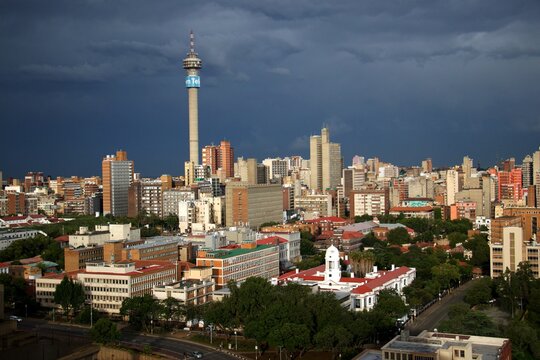 overview over downtown of Johannesburg with TV-tower and dark thunder clouds with sun