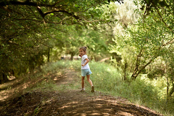 A girl runs under the trees.